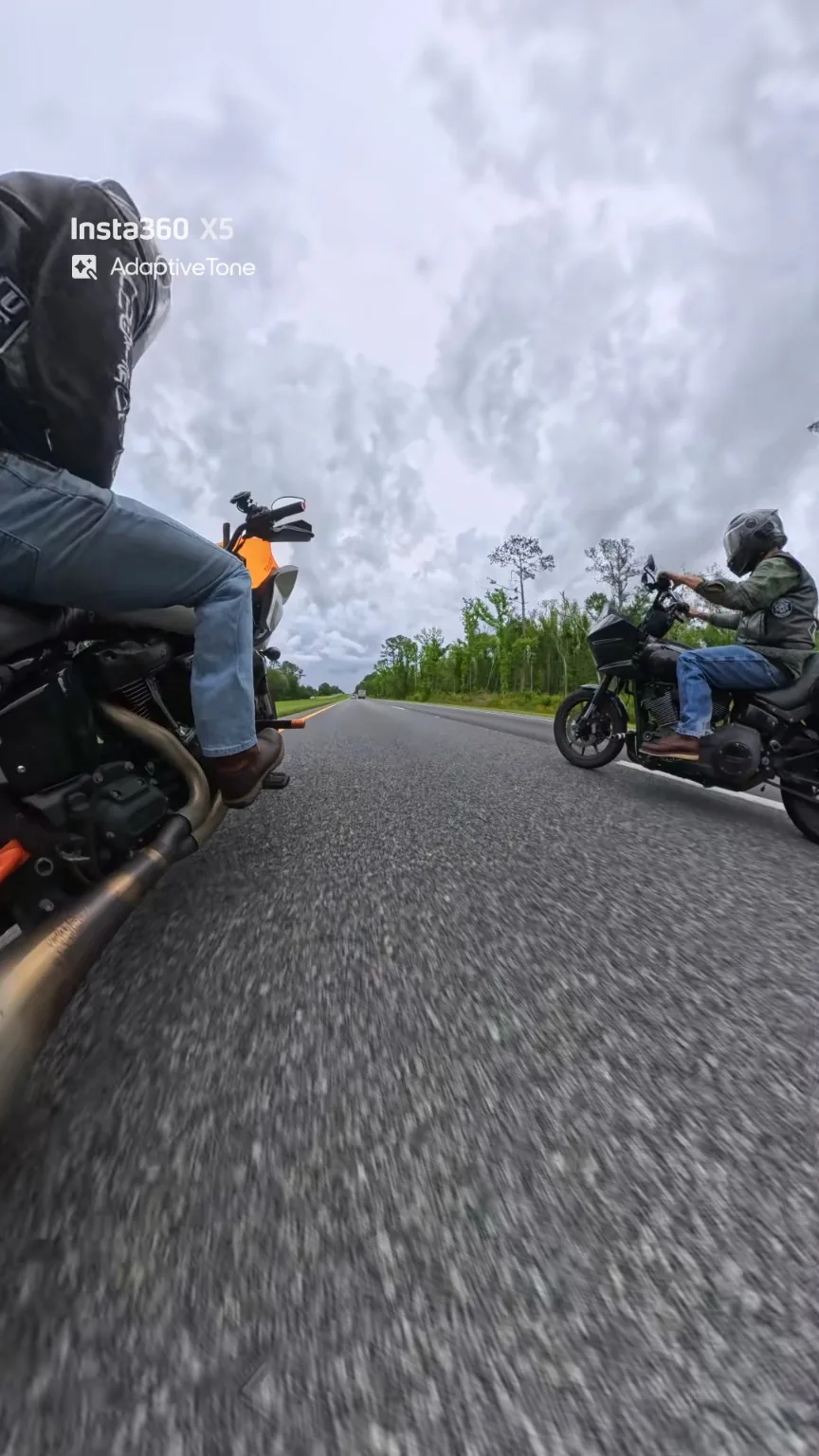Two motorcyclists riding beside one another, photographed close to the road.
